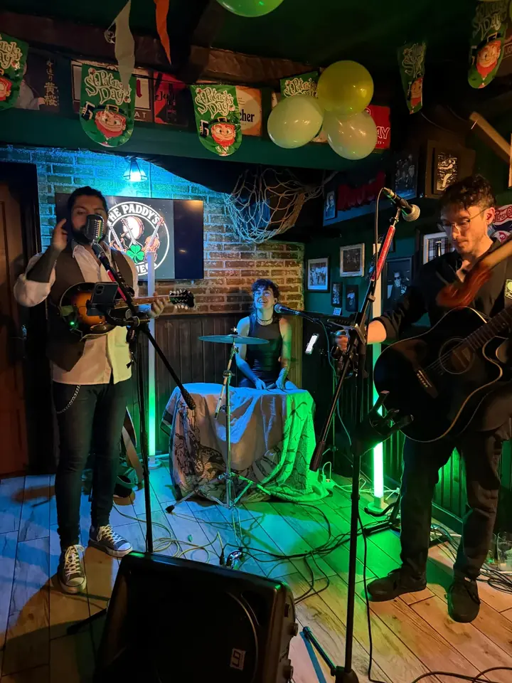 La banda tocando en el bar entre banderines verdes y naranjas.