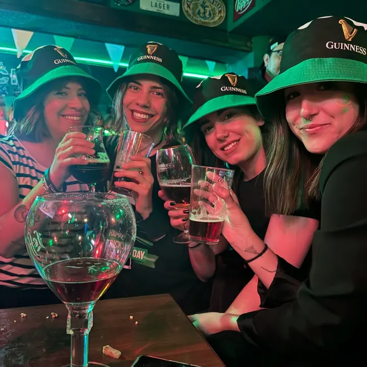 Un grupo de amigas con gorros verdes brindando en San Patricio.